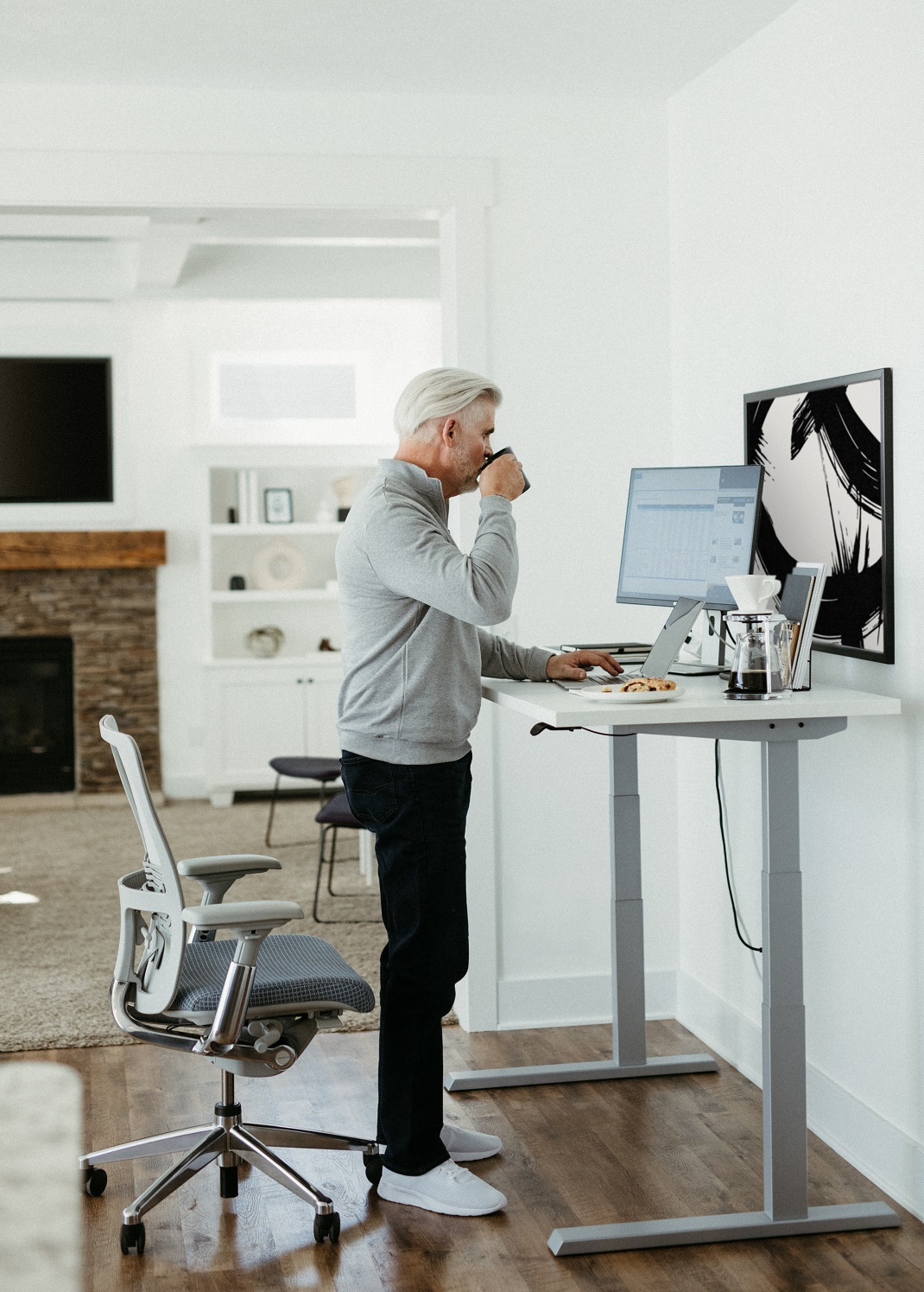 Man standing at Upside height-adjustable table with Zody chair.